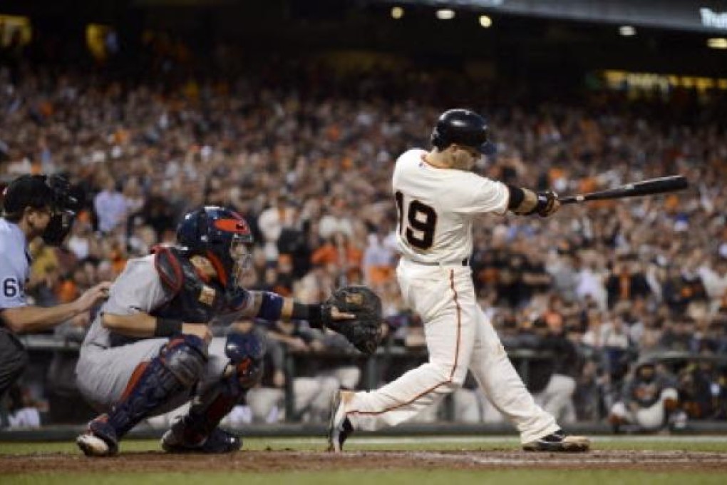 San Francisco Giants second baseman Marco Scutaro (right) hits a single with the bases loaded as St. Louis Cardinals catcher Yadier Molina looks on. Photo: EPA