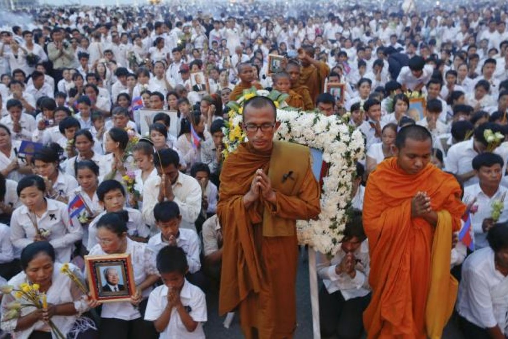 Thousands of mourners in white pray at the gates of the Royal Palace in Phnom Penh. Photo: Reuters