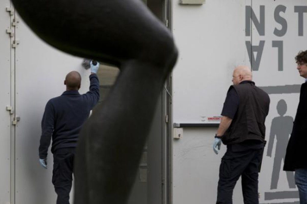 Forensic experts dust the inside of a back door for fingerprints at Kunsthal museum in Rotterdam, Netherlands, on Tuesday. Photo: AP