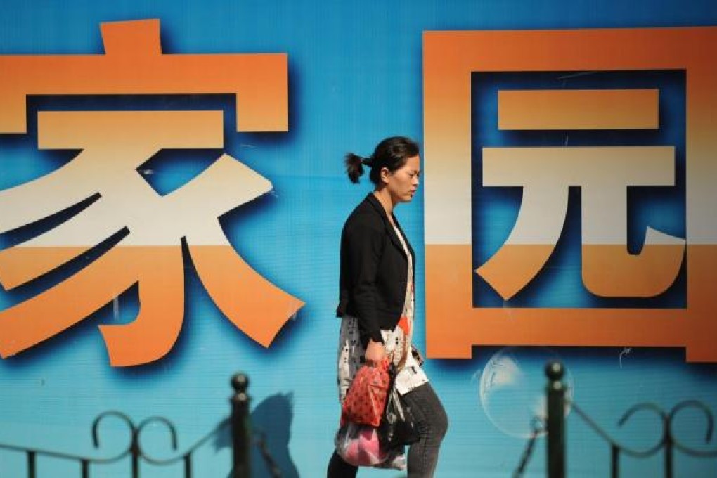 A woman passes a property project sign in Shanghai. Photo: AFP