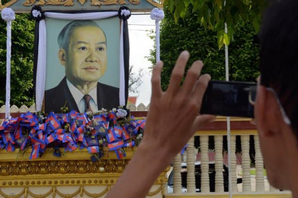 A Cambodian man photographs a portrait of the late former King Norodom Sihanouk near the Royal Palace in Phnom Penh on Thursday. Photo: AFP