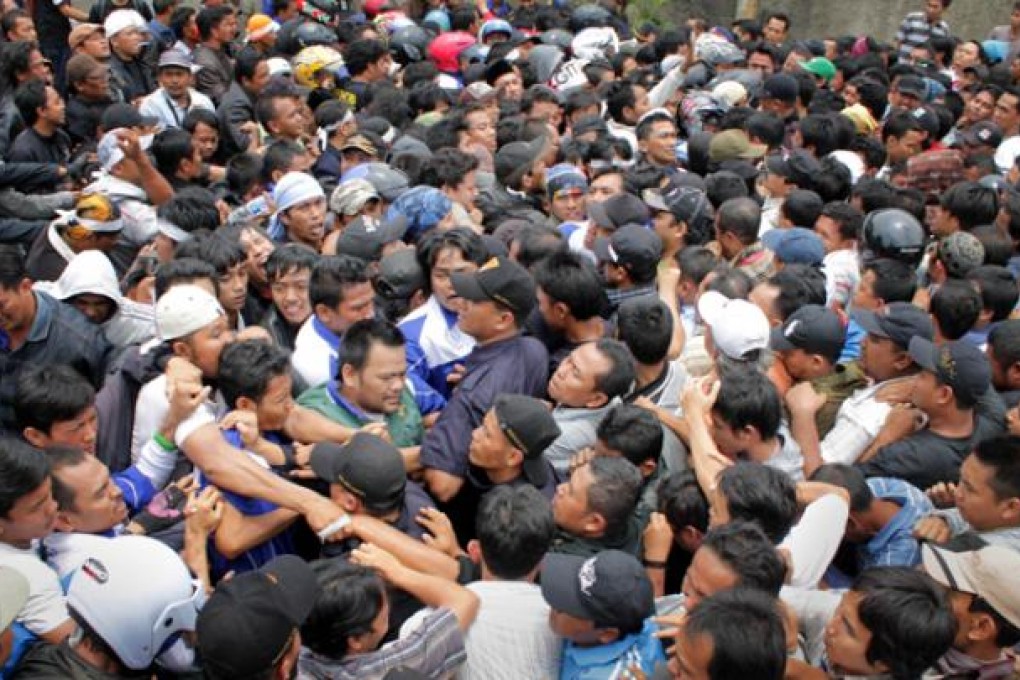 Protestors (left) clash with company security personnel and new employees (right) outside Panarub Dwikarya factory in Tangerang on Thursday. Photo: AFP