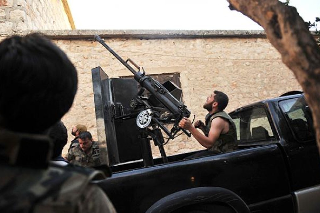 A rebel fighter fires an anti-aircraft gun as a Syrian army helicopter flies overhead in Maarat al-Numan. Photo: AFP