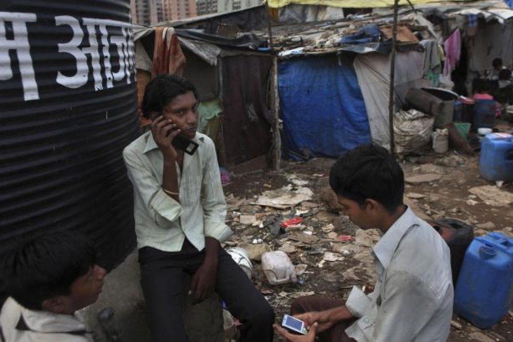 Young men on their mobile phones in a slum in Mumbai, India; a country where according to the United Nations, more people have mobile phones than access to a toilet. Photo: AP