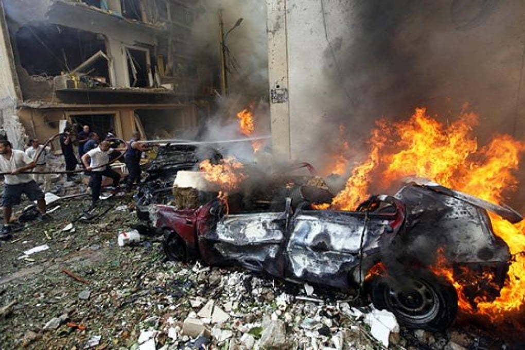 Firefighters extinguish burning cars after an explosion in Achrafiyeh, Beirut. Photo: AP