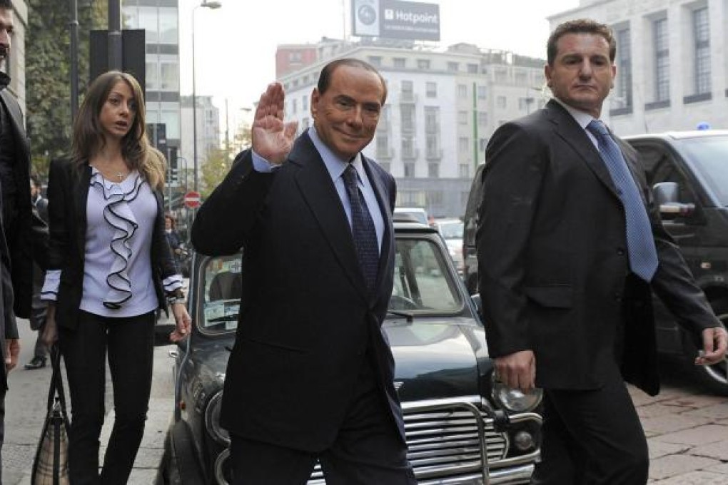 Silvio Berlusconi waves as he arrives yesterday at the court hearing in Milan, at which he denied hosting kinky parties. Photo: AP