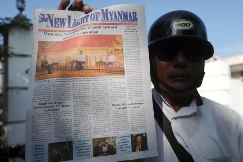 A Myanmar vendor shows a copy of the new version of the government-run ' The New Light of Myanmar' with a coloured front-page photo in Naypyidaw.