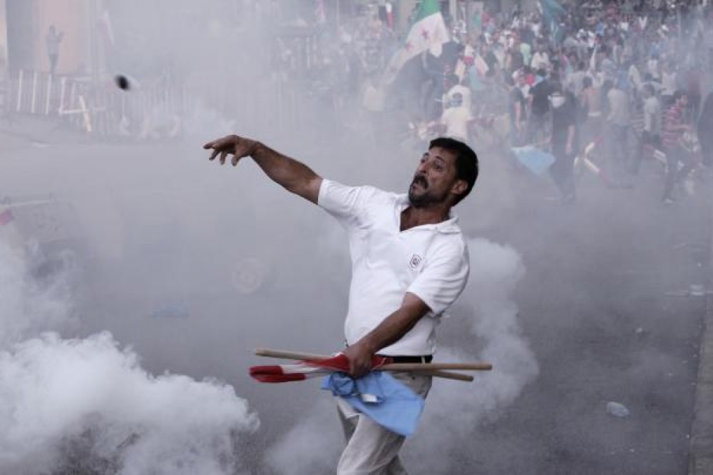 A protester throws a tear gas canister back at security forces during clashes after Wissam al-Hassan's funeral. Photo: AP