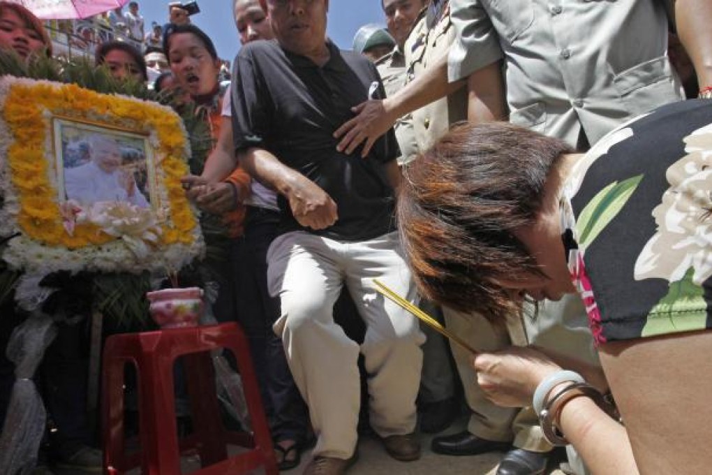 The suspect prays before the late king's portrait. Photo: EPA