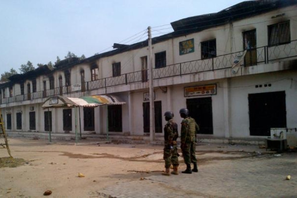 Soldiers stand outside a burnt out shopping mall in Maiduguri, Nigeria on October 8. Photo: AP