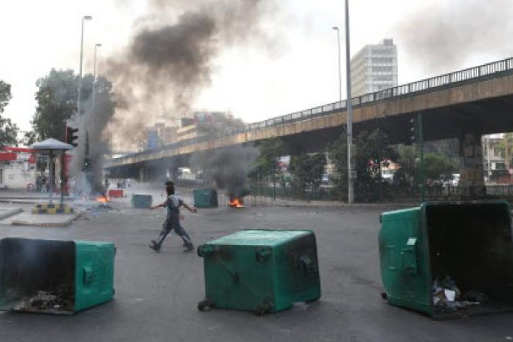 Lebanese cross between burning tyres and garbage containers laid by protesters after overnight clashes between Sunni and Shiite gunmen, in Beirut, Lebanon on Monday. Photo: AFP