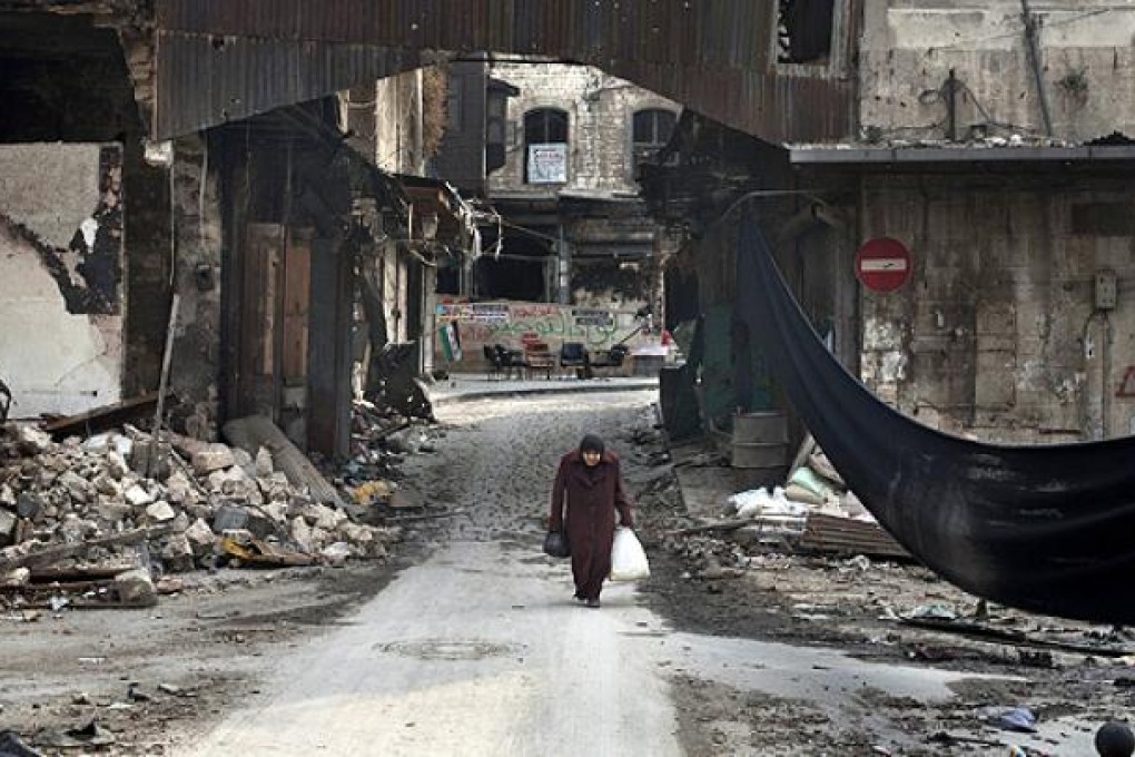 An Syrian woman crosses a street next to a black cloth used to separate the area from Syrian government forces' snipers fire in Aleppo. Photo: AFP