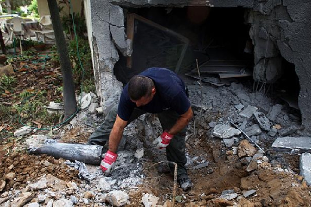 A member of an Israeli bomb squad unit surveys the scene where a rocket fired by Palestinian militants in Gaza landed in Kibutz Reim. Photo: Xinhua