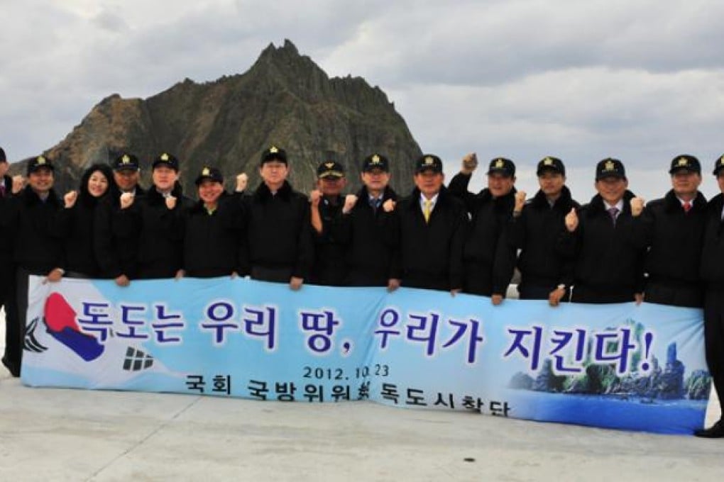 Members of South Korea's parliamentary National Defence Committee hold a banner reading 'Dokdo is Korean territory, we defend!' during a visit to the Dokdo islands (known as Takeshima in Japan) on Tuesday. Photo: AFP
