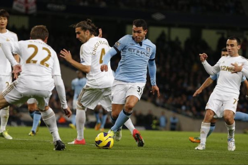 Manchester City's goal hero Carlos Tevez (centre) runs through the Swansea defence during their English Premier League match at the Etihad Stadium. Photo: Reuters