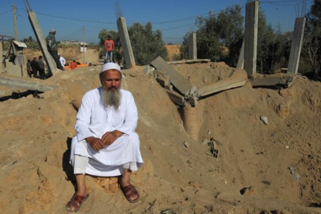 A Palestinian man sits on th edge of a crater following an Israeli attack that damaged a building in al-Bureij, in the centre of the Gaza Strip, on Monday. Photo: AFP