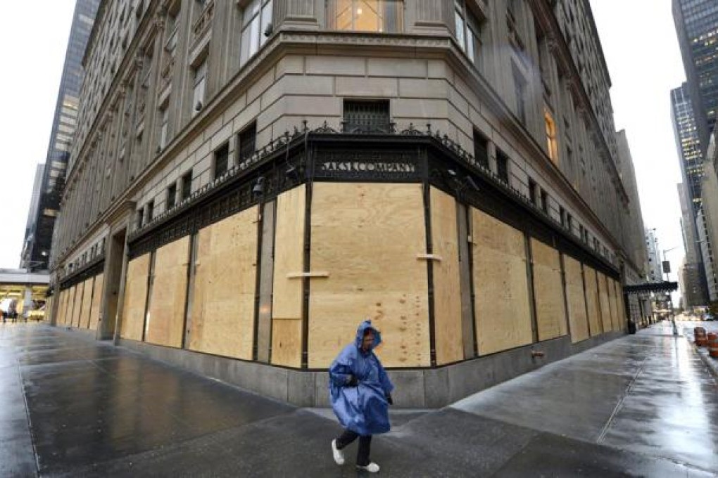 A woman walks past a boarded-up Saks Fifth Avenue as New York braces for Sandy’s wrath. Photo: AFP