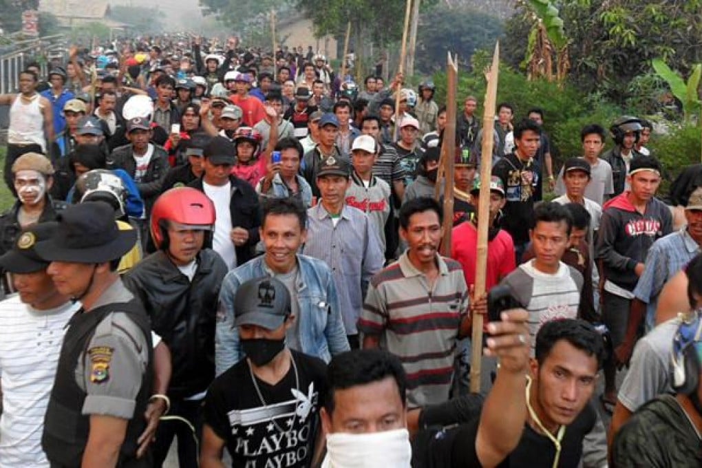 Villagers carry wooden sticks during clashes in Lampung. Photo: EPA