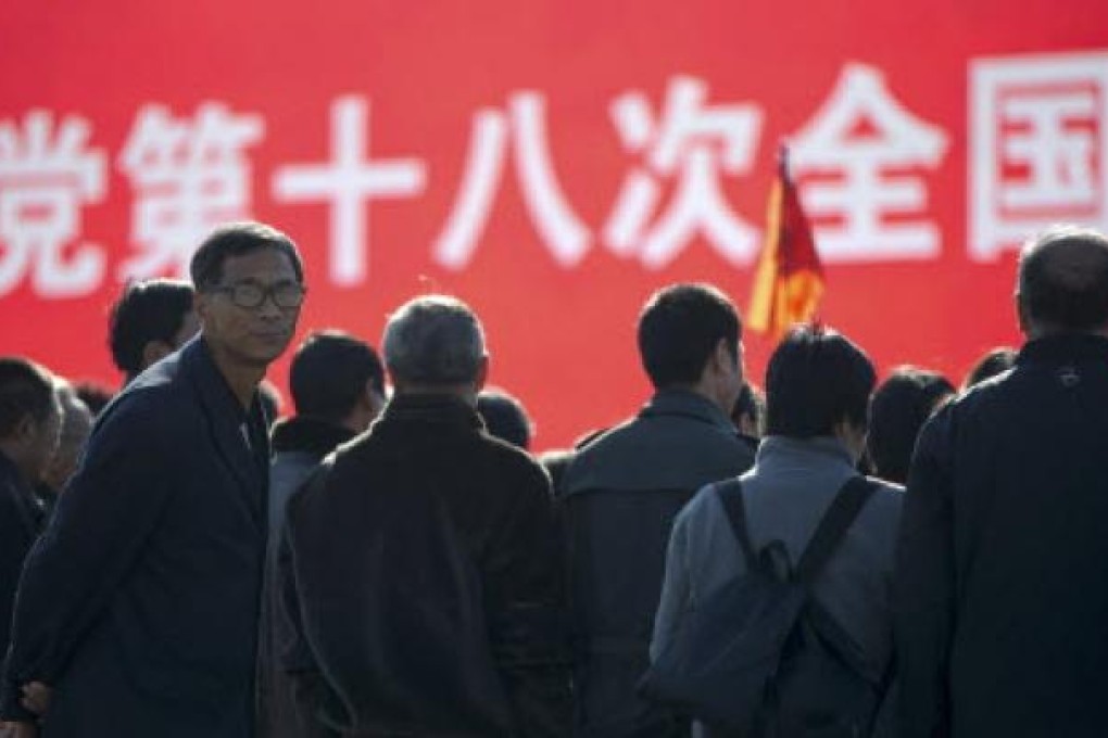 A man looks back as people gather in front of the screen displaying the words "18th party congress" at Tiananmen Square. Photo: AP
