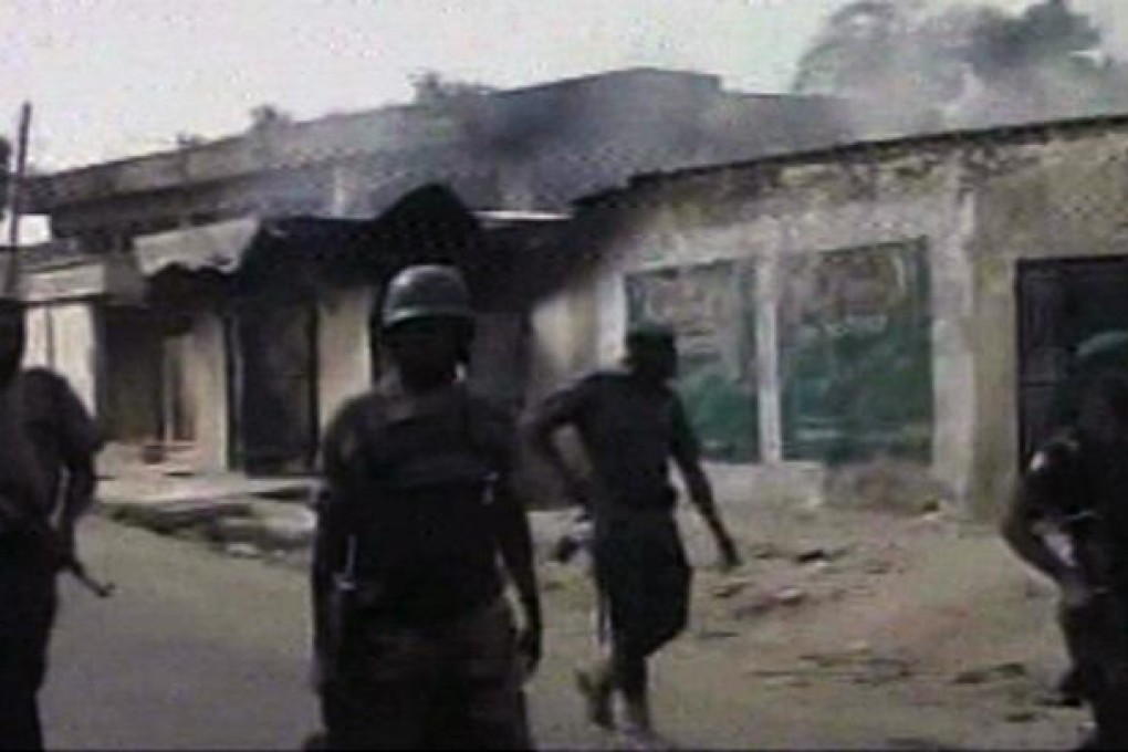 Nigerian soldiers walk past burnt out houses in Maiduguri on October 8. Photo: AP
