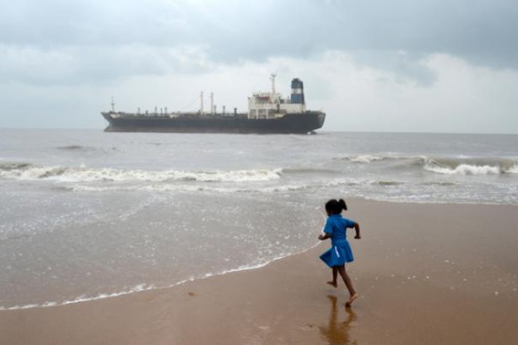 An Indian girl runs on the beach near the Pratibha Cauvery, which ran aground during Cyclone Nilam, on Thursday. Photo: Xinhua