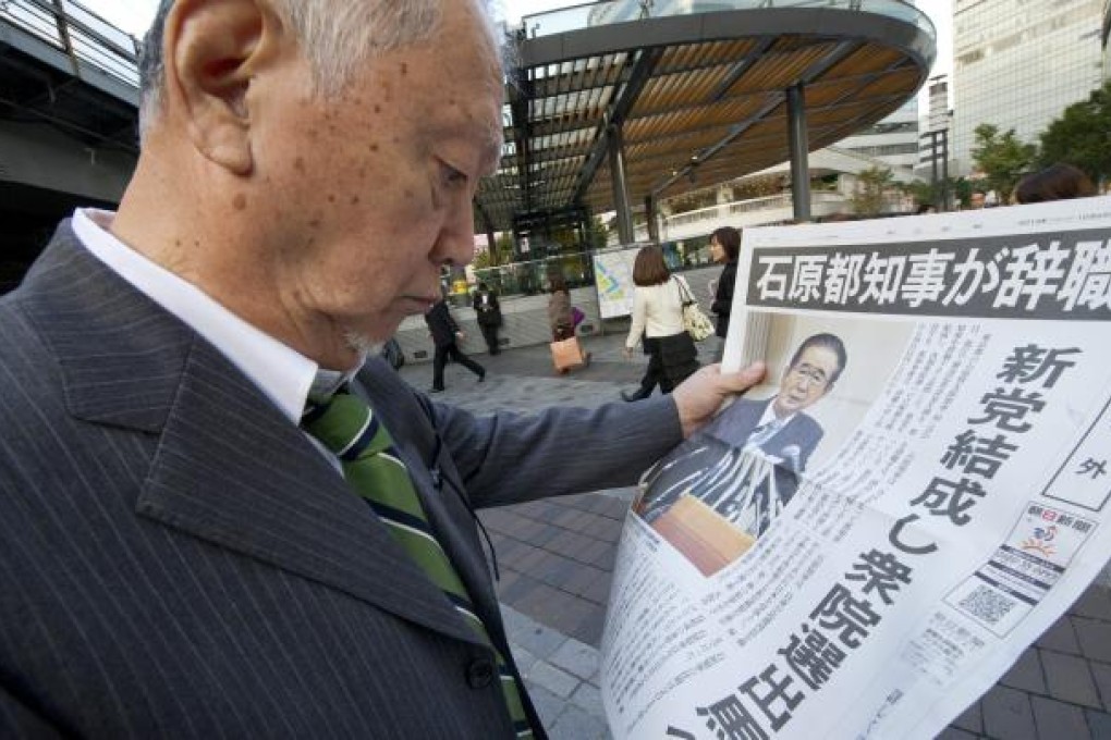 A Japanese pedestrian reads a breaking edition newspaper announcing the resignation of Tokyo Governor Shintaro Ishihara in Tokyo. Photo: EPA