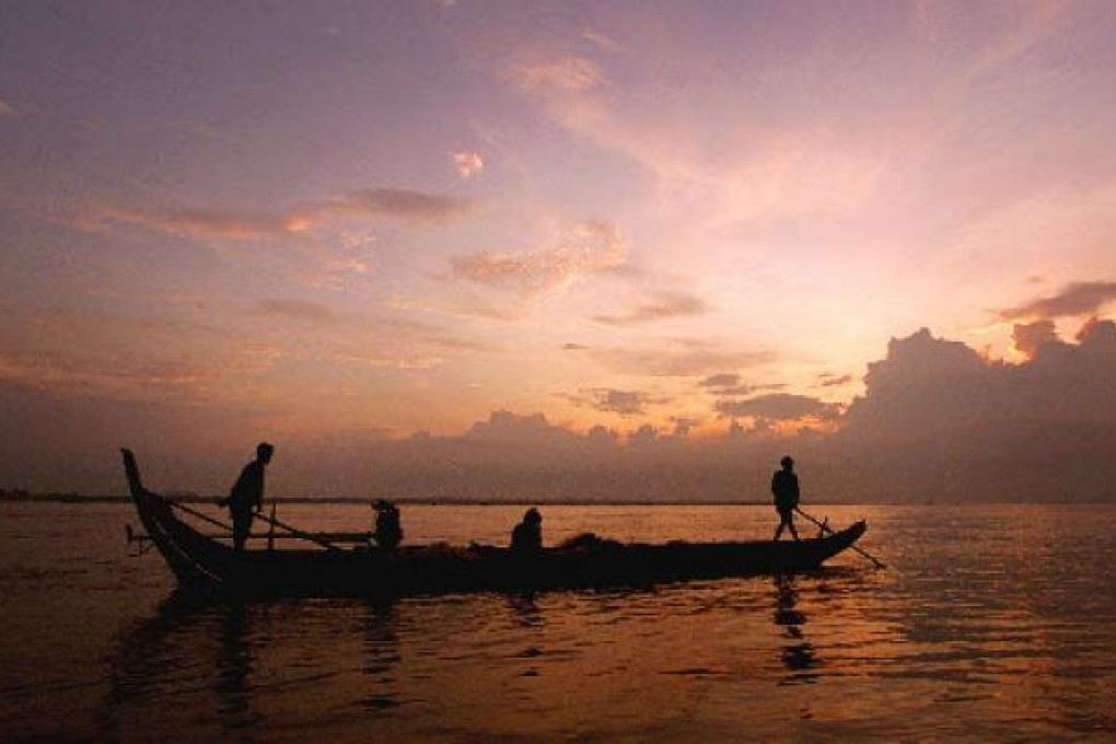 Dawn breaks over the Mekong River as a small fishing boat drifts downstream casting it's net in Phnom Penh, Cambodia. Photo: AP