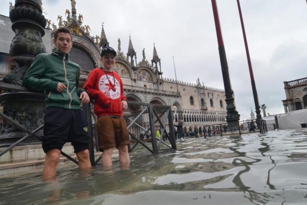 People stand in the flooded streets of Venice, November 1, 2012. Photo: EPA