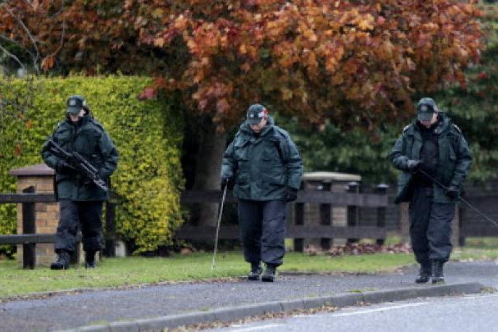 Northern Ireland police officers search the area close to a fatal shooting of a prison officer near Lurgan. An Irish nationalist has been arrested in connection with the shooting. Photo: AP