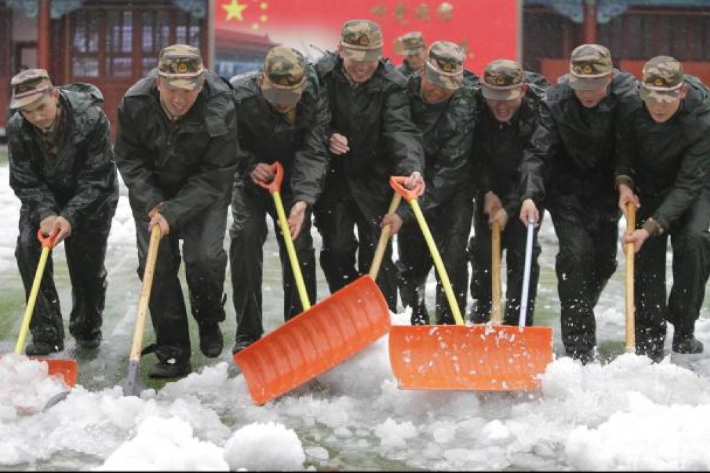 Paramilitary police shovel wet snow at the Forbidden City yesterday. Photo: Reuters