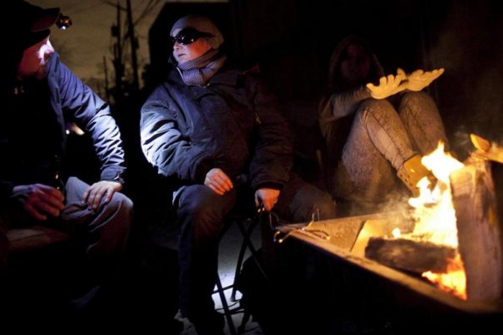 Residents in the Rockaway neighbourhood of Queens keep warm by lighting a fire in the street after their homes were damaged by superstorm Sandy. Photo: AFP