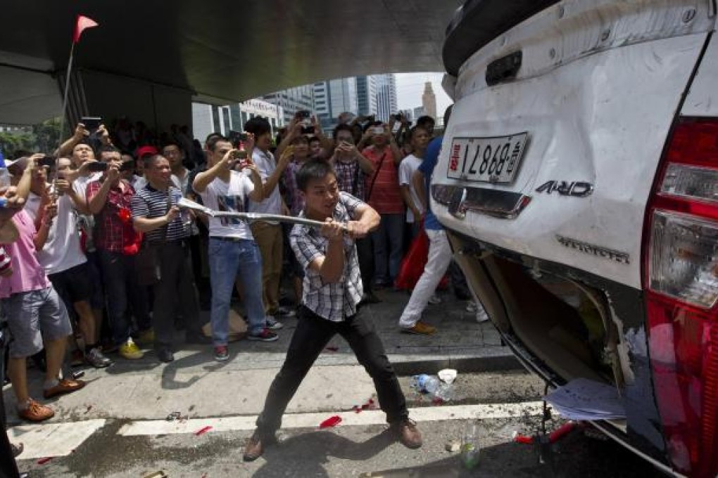 A protester destroys a Japanese-brand police car in an anti-Japan protest in Shenzhen. Photo: Reuters