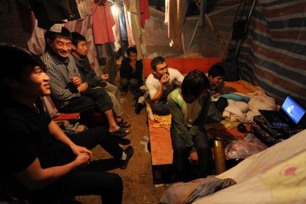 Migrant workers watching a video on a laptop under a self-built shelter shared with several hundred others in Hefei, central China's Anhui province. Photo: AFP