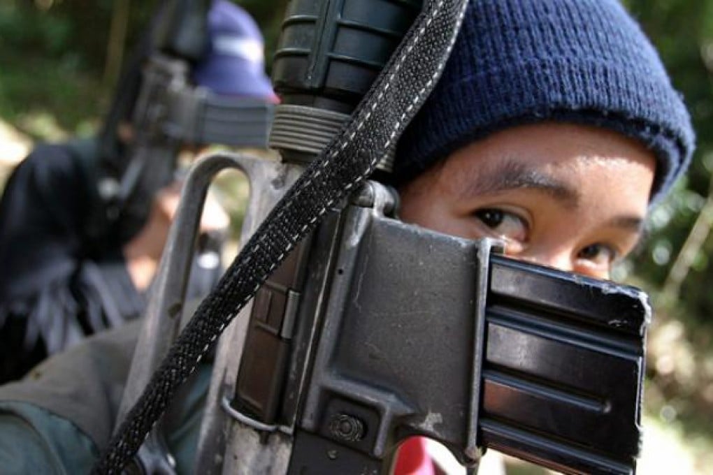 A female New People's Army (NPA) guerilla covers her face with an M16 armalite rifle. Photo: EPA