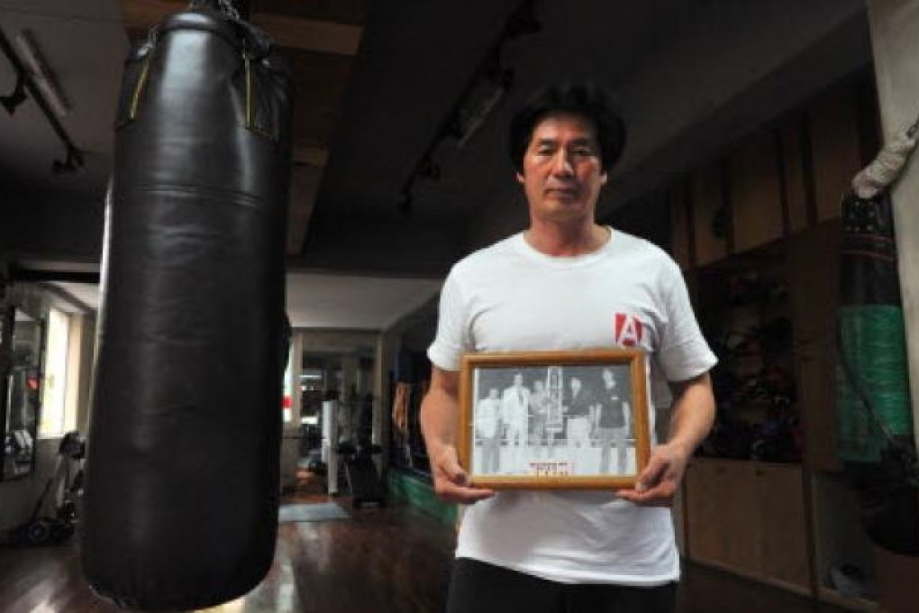South Korean trainer Kim Yoon-Gu, 56, holds a picture showing boxer Kim Duk-Koo with a trophy, at his gym in Seoul. Kim Duk-Koo died after a bout with world lightweight champion, Ray "Boom Boom" Mancini in Las Vegas in 1982. Photo: AFP