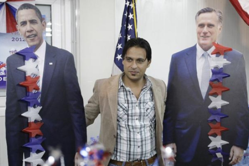 An Afghan man poses next to cutout figures of President Barack Obama (left) and Mitt Romney at the US Embassy in Kabul on Wednesday. Photo: AP