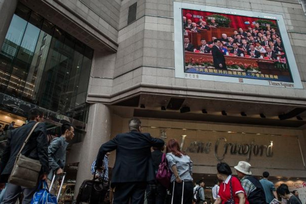 People watch a large screen showing a news broadcast recorded in Beijing during the opening of the 18th Communist Party Congress, in Hong Kong on November 8, 2012. Photo: AFP