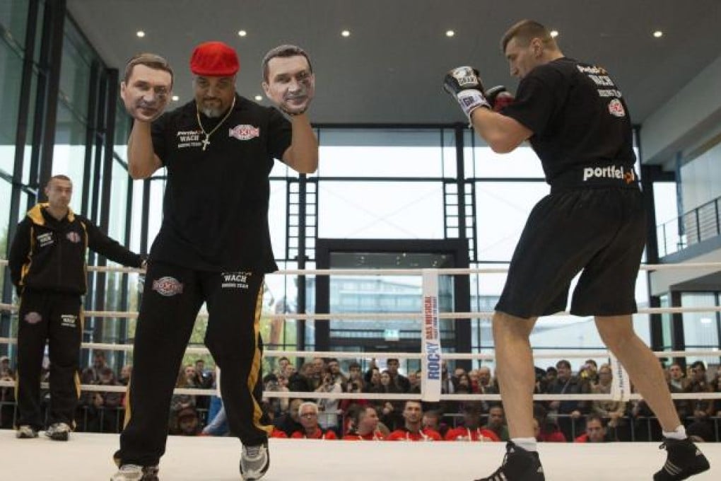 Juan de Leon, coach to Mariusz Wach (right) holds up sparring gloves with images of Wach's rival Vladimir Klitschko during a training session in Hamburg. Photo: Reuters