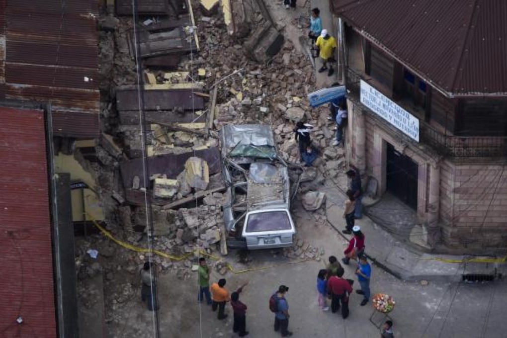 Guatemalans stand among the destruction of the quake. Photo: AP