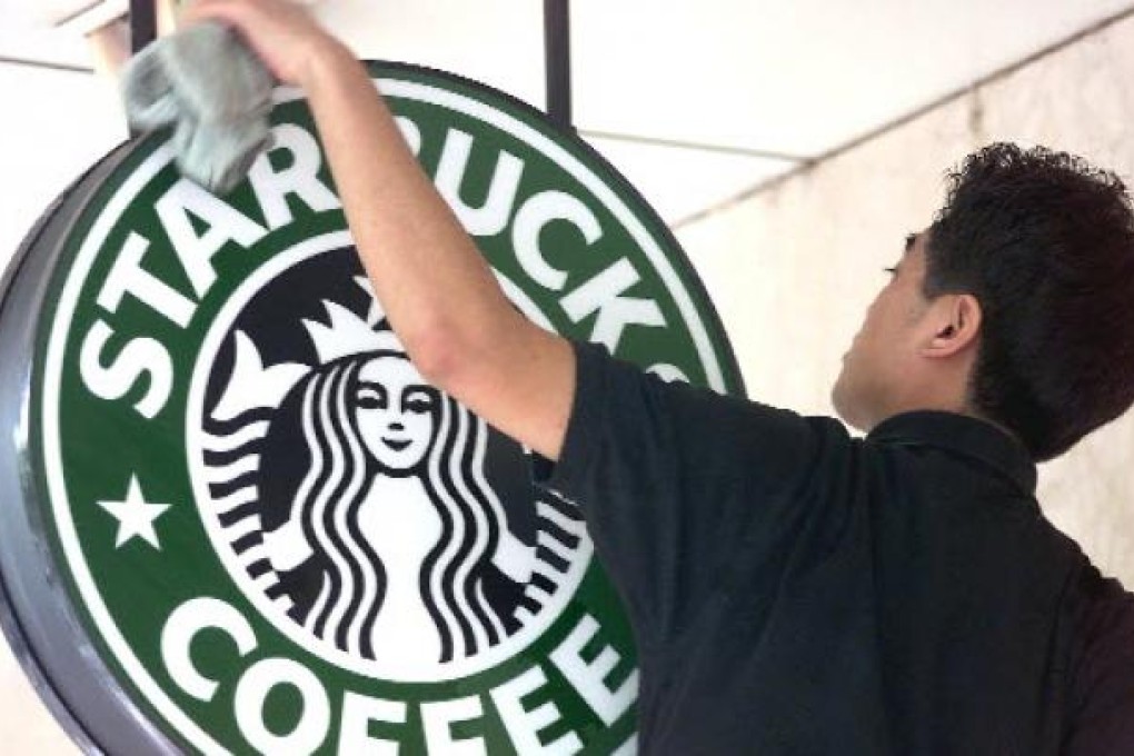 A worker cleans the sign outside a global coffee franchise Starbucks outlet in Beijing. Photo:AFP