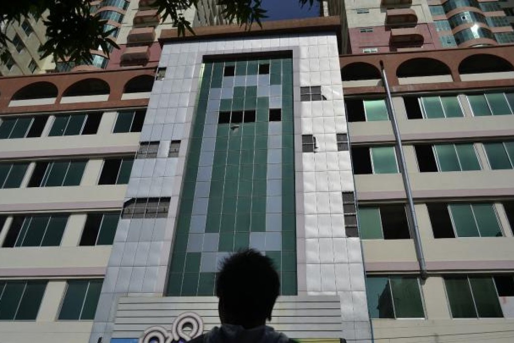 A man looks at the facade of Mandalay's highest building, the 25-storey Mann Myanmar Plaza, from where several window panes are missing after they fell following a 6.8-magnitude quake. Photo: AFP