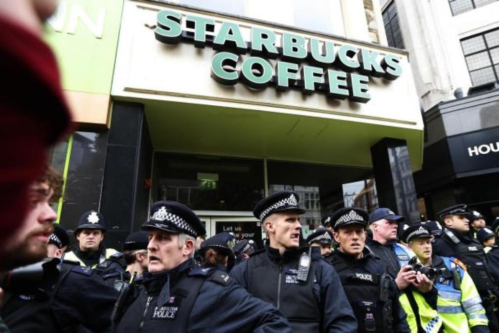 Police protect a Starbucks branch during an anti-cuts march last month after the company's low tax bill was reported. Photo: Reuters