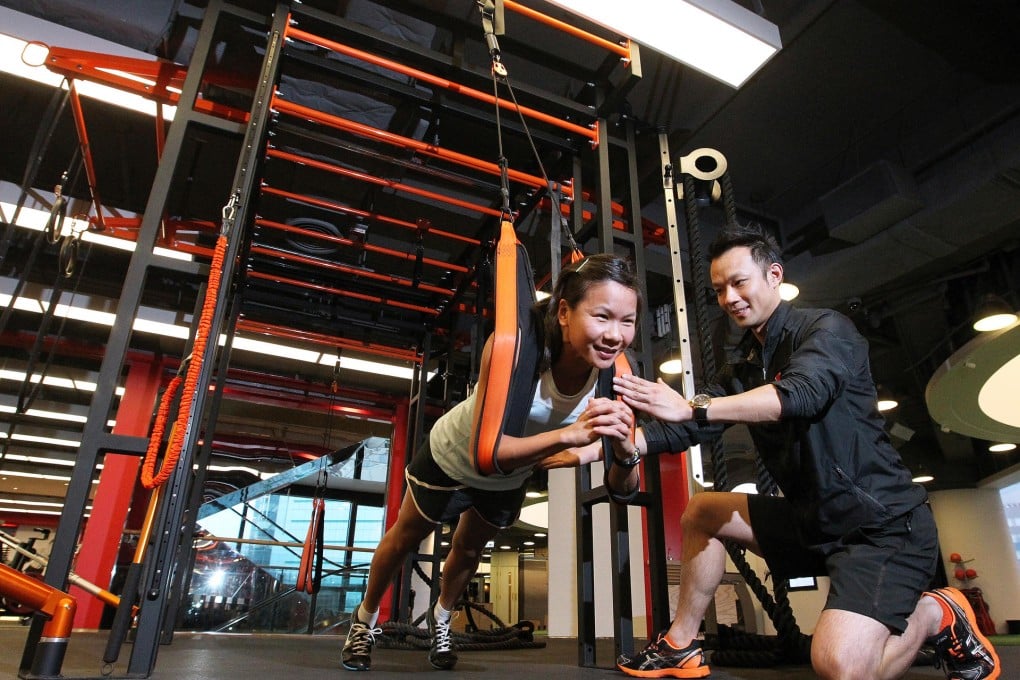 Personal trainer Alan Pak puts health editor Jeanette Wang through her paces with the PurMotion functional training equipment. The system uses ropes to train the body through a series of movements. Photos: May Tse