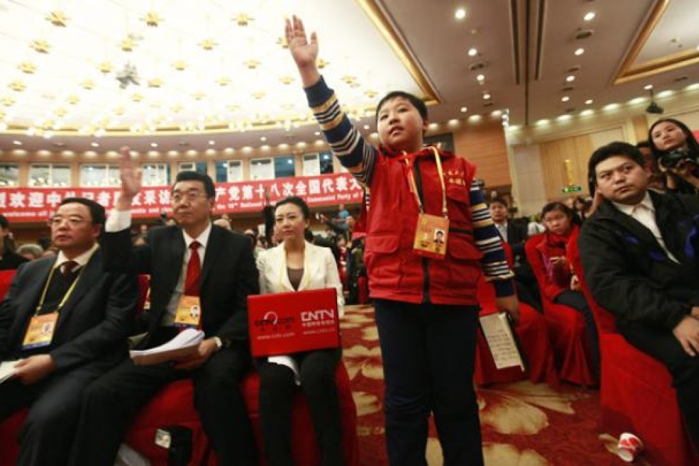Eleven-year-old Zhang Jiahe raises his hand during a press conference on the sidelines of the 18th Communist Party Congress in Beijing on Monday. Photo: EPA