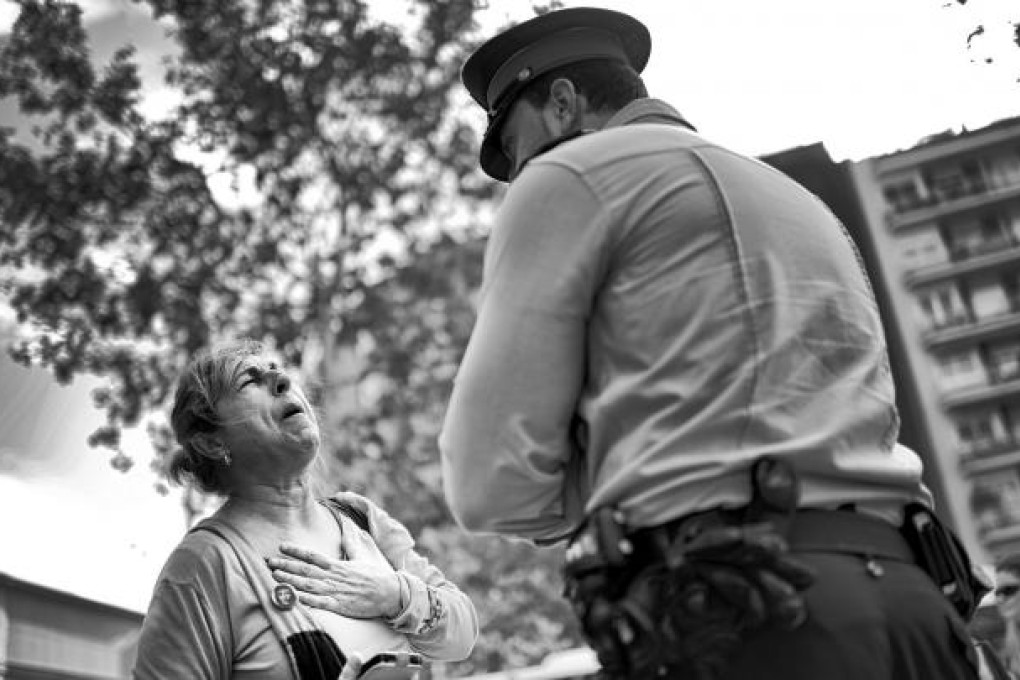 A woman confronts a police officer at the entrance of an office of Catalunya Caixa Bank during a protest against the institution in Barcelona. Photo: NYT