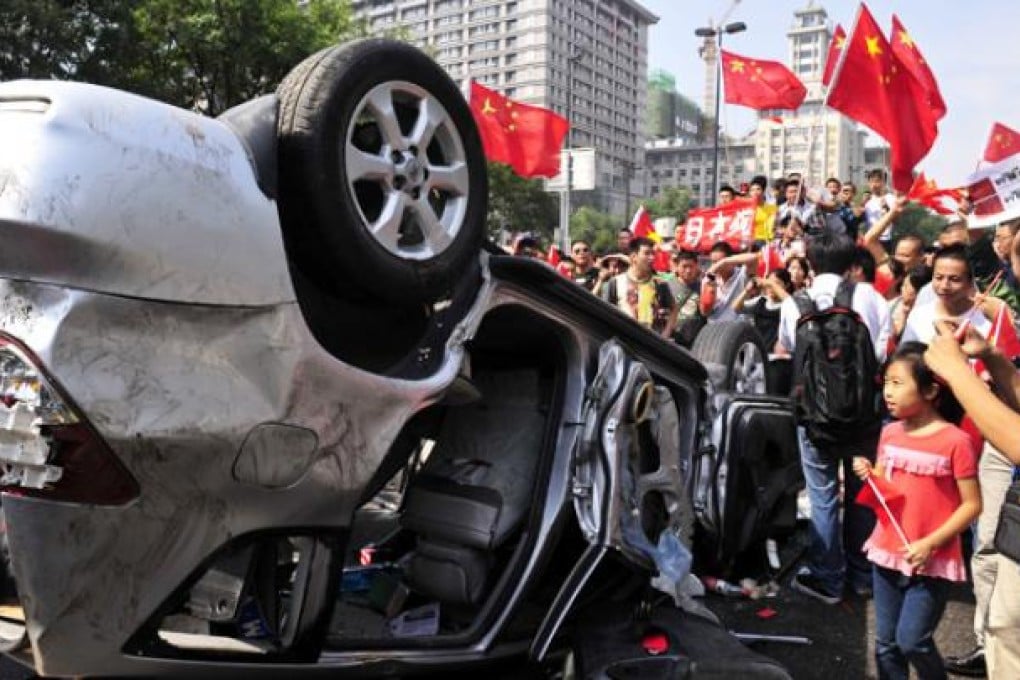 Demonstrators hold Chinese flags and banners beside an overturned Japanese brand car during a protest in Xi'an, Shaanxi province on September 15. Photo: Reuters