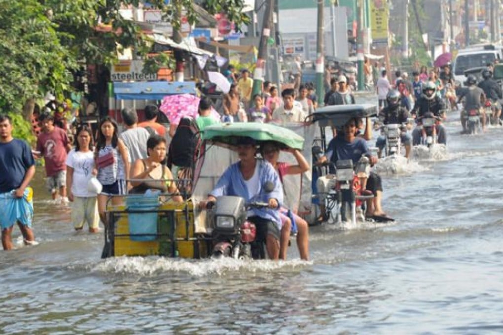 Residents commute along a flooded stretch of road in Calumpit town, north of Manila on August 11. Photo: AFP