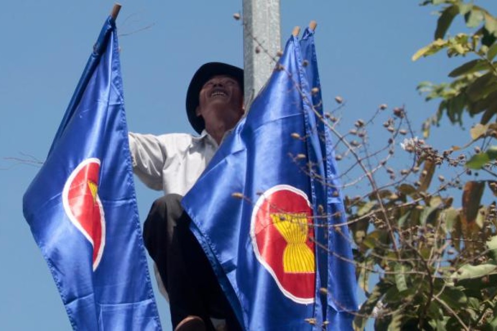 A Cambodian worker puts up Asean flags along the road from the airport into downtown Phnom Penh, ahead of the 21st Asean Summit (15-20 November 2012). Photo: EPA