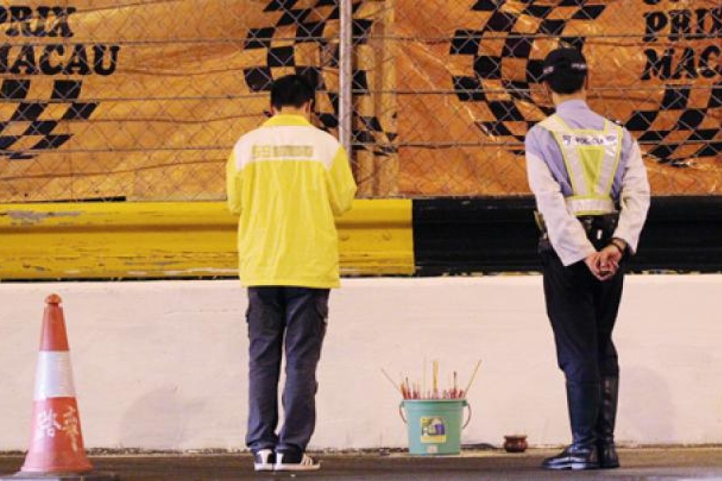 A man pays his respects to Hong Kong racing driver Phillip Yau Wing-choi at Mandarin Bend, the spot where the driver died in an accident during the CTM Macau Touring Car Cup qualifying session on Friday. Photo: Nora Tam