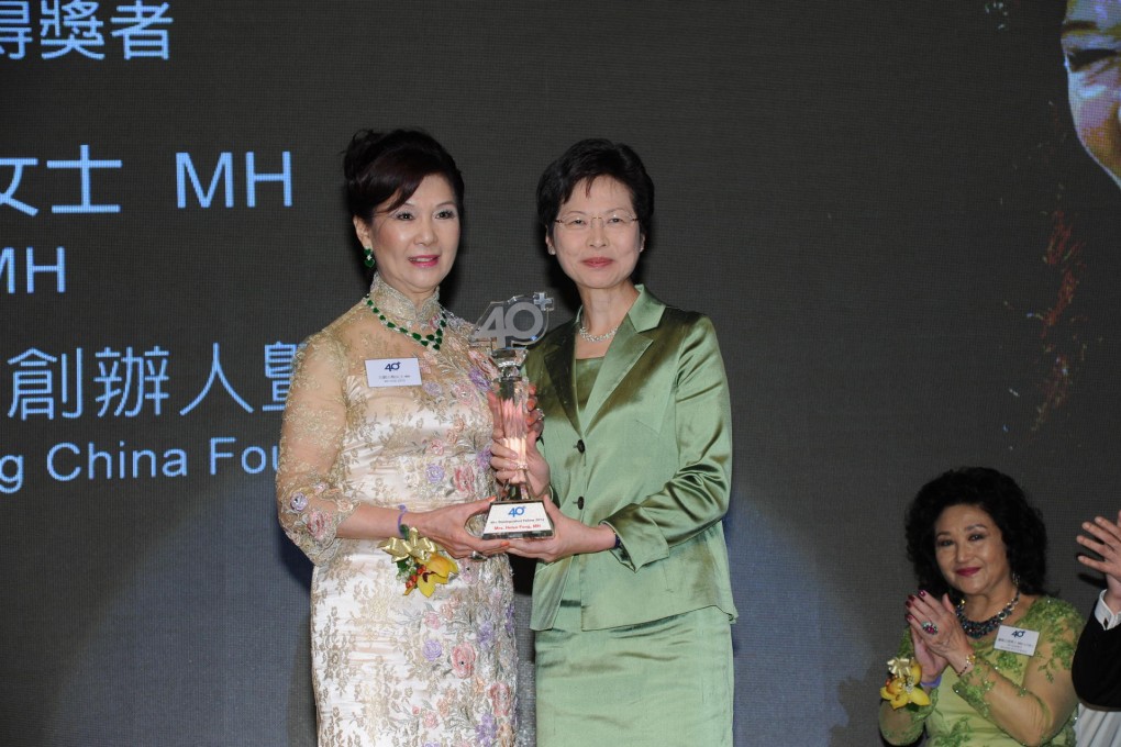 Helen Fong (left) receiving her award from Carrie Lam.